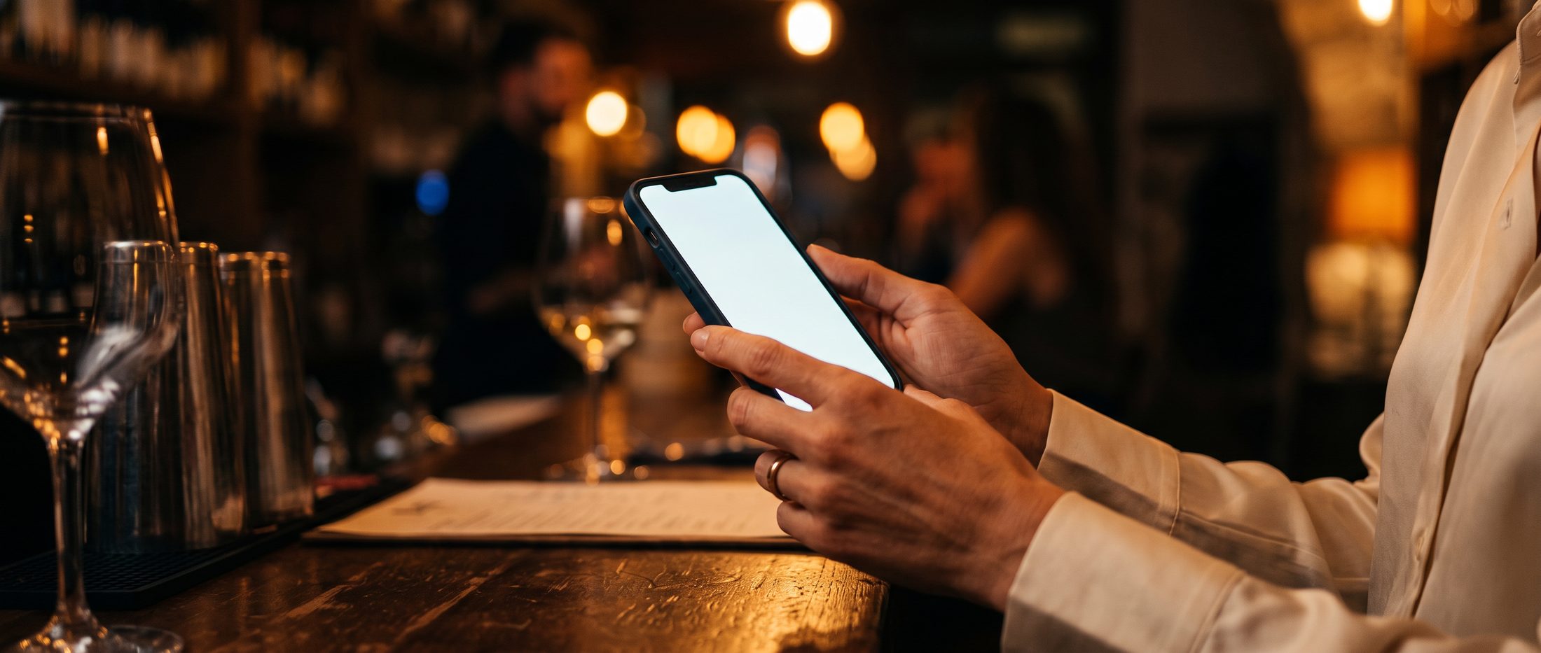 Manos sosteniendo un teléfono en la barra de un bar